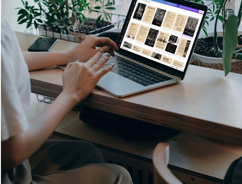 K&ouml;nnte beinhalten: Eine Person arbeitet an einem silbernen Laptop mit einem wei&szlig;en Bildschirm, auf dem ein digitales Dokument mit mehreren Seiten angezeigt wird. Das Dokument hat einen braunen Hintergrund mit schwarzem Text und Bildern. Der Laptop steht auf einem hellbraunen Holztisch.