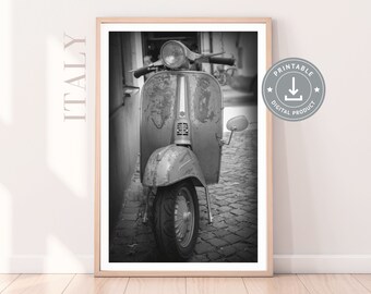 May include: Black and white photograph of a vintage Vespa scooter parked on a cobblestone street in Italy. The scooter is slightly weathered and has a worn, rustic look.