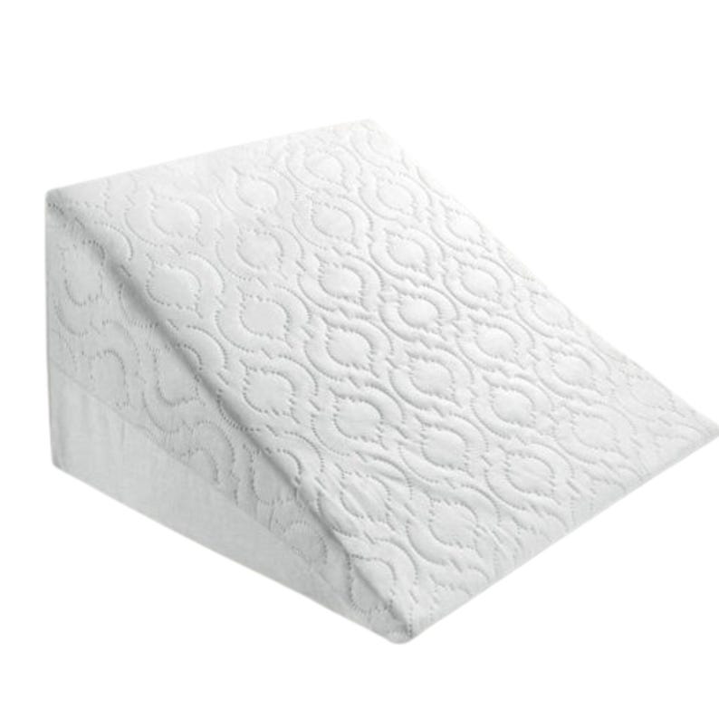 May include: White wedge pillow with a quilted pattern. The pillow is designed to elevate the head and shoulders for comfort and support.