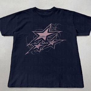 May include: A navy blue t-shirt with a pink graphic of three stars in a stylized design. The stars are outlined in black and have a faded, distressed look.