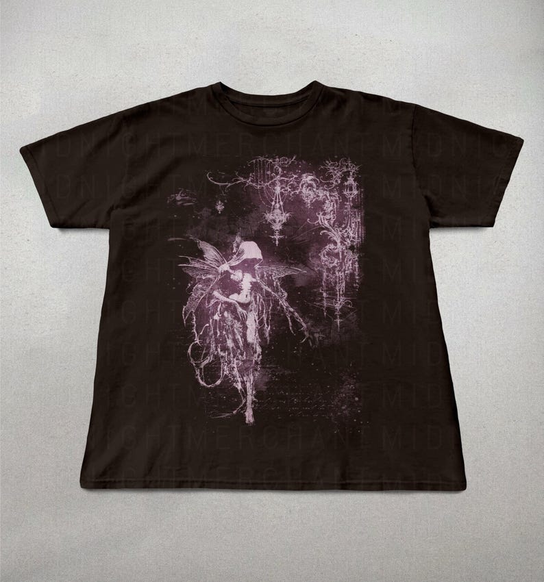 May include: Dark brown t-shirt featuring a detailed, gothic-style illustration in shades of purple and white. The design includes a figure with wings and intricate, ornamental elements. The shirt is made of a soft material.