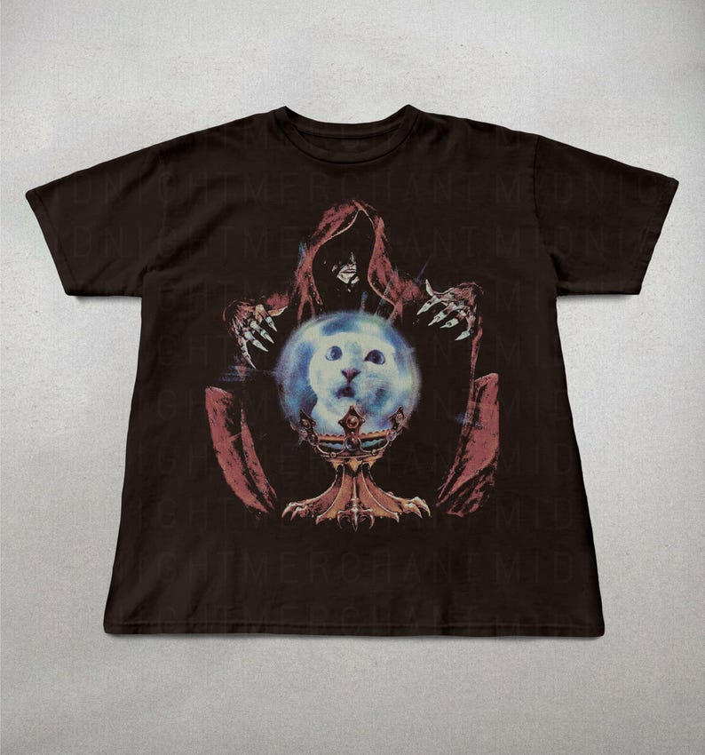 May include: Dark brown t-shirt featuring a graphic design. The design depicts a hooded figure with outstretched hands, holding a glowing orb with a cat's face. The orb rests on a decorative chalice. The design is in shades of red, blue, and white.