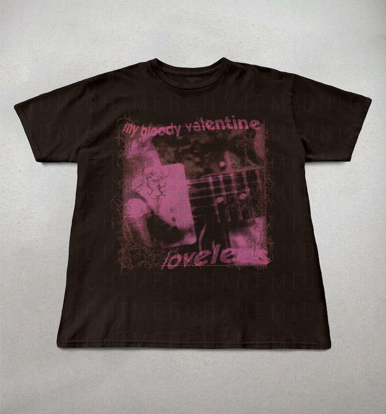 May include: A dark brown t-shirt featuring a pink graphic with the text "my bloody valentine" and "loveless". The graphic appears to be a blurred image of a guitar. The shirt is a short-sleeved crew neck.