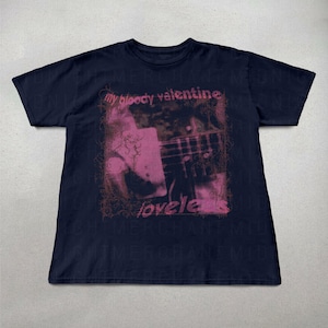May include: Navy blue t-shirt featuring a pink and brown graphic with the text "my bloody valentine" and "loveless". The graphic appears to be a photograph of a guitar and a person. The shirt is a short-sleeved crew neck.