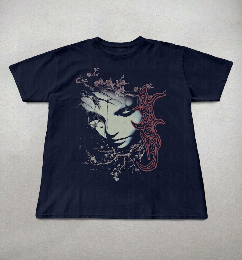 K&ouml;nnte beinhalten: Marineblaues T-Shirt mit einem grafischen Aufdruck eines stilisierten Frauengesichts, floralen Elementen und einem abstrakten Design in Rosa und Wei&szlig;. Das Design hat ein gotisches Thema.