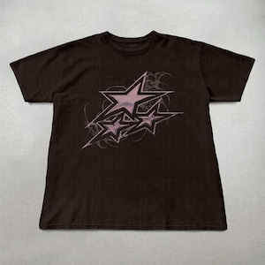 May include: Black t-shirt with a pink graphic of three stars with a swirling design. The text "NIGHTMERCHANT" is repeated in a faded print on the shirt.