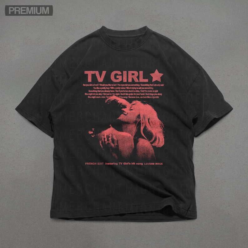 May include: Dark grey t-shirt with the red text "TV GIRL" and a star. A red graphic of a couple kissing is below the text. The shirt also features song lyrics and the text "FRENCH EXIT featuring TV Girl's hit song LOVERS ROCK."