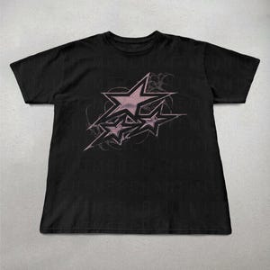 May include: Black t-shirt with a pink graphic of three stars on a black background. The stars are stylized and have a faded look.
