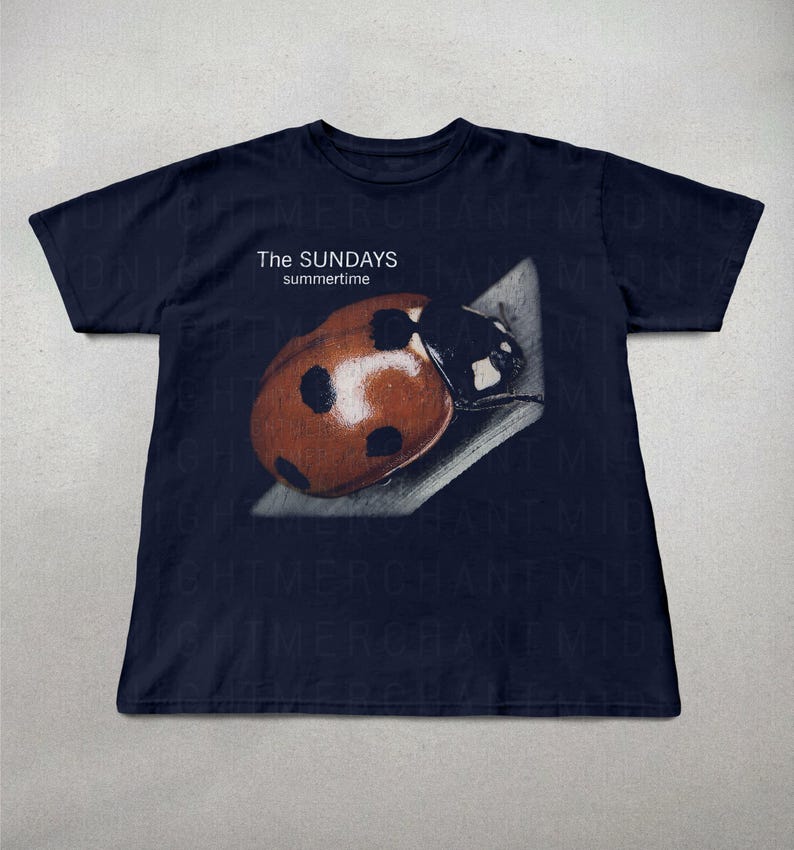 Pode incluir: T-shirt azul marinho com uma imagem de uma joaninha e o texto "The Sundays summertime". A joaninha &eacute; castanha com manchas pretas. Uma camiseta casual para uso di&aacute;rio.