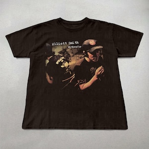 May include: A dark brown t-shirt with a graphic of a person wearing a cap, and the text "Elliott Smith either/or" in white. The image has a vintage, slightly faded appearance, suggesting a retro or music-related theme.