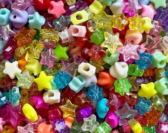 Puede incluir: Un vibrante surtido de cuentas de colores en varias formas, incluyendo estrellas, óvalos y formas redondas. Las cuentas son en tonos de rosa, amarillo, verde, azul, naranja y morado. Las cuentas son de un material translúcido.