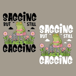 以下が含まれることがあります： ピンクのブラとスカートを着た緑色のカエルが歩行器を使って歩いている。カエルは緑の草とピンクの花に囲まれている。「Sagging but still gagging」という文字がカエルの上と下に黒文字で書かれている。