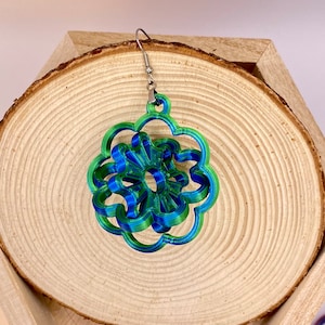 May include: A pair of blue and green 3D printed earrings in the shape of a flower. The earrings are hanging from silver hooks.