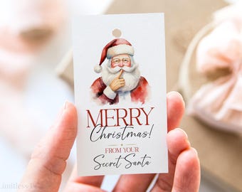 May include: A rectangular gift tag featuring a watercolor illustration of Santa Claus with a finger to his lips. The tag reads "MERRY Christmas! FROM YOUR Secret Santa" in a mix of serif and script fonts. The tag has a hole at the top.