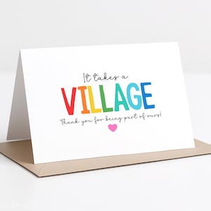 Pode incluir: Um cartão branco com o texto "It takes a VILLAGE" em letras coloridas. O cartão inclui a frase "Thank you for being part of ours!" e um coração rosa. O cartão está dentro de um envelope bege.