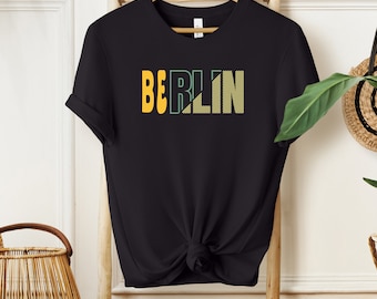 May include: Black t-shirt with a graphic print of the word "BERLIN" in yellow and green.