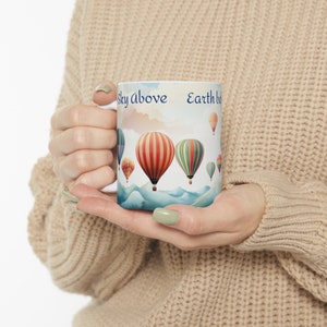 May include: White ceramic mug with a colorful hot air balloon design and the text "Sky above Earth below".