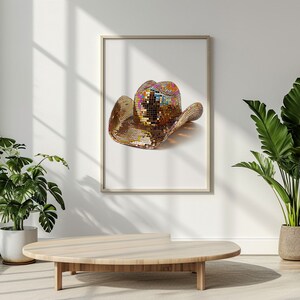 K&ouml;nnte beinhalten: Ein goldener Cowboyhut mit schillernden Pailletten, gerahmt und an einer wei&szlig;en Wand in einem modernen Ambiente ausgestellt.