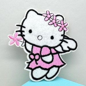 May include: An embroidered patch of a cartoon cat in a pink dress, holding a pink flower, and wearing a floral headband. The cat has black eyes, whiskers, and a black outline. The patch is white.
