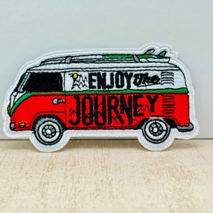 Peut inclure: Écusson brodé représentant un van rouge, blanc et vert avec les mots "ENJOY the JOURNEY". Le van a une planche de surf sur le toit et des pneus noirs. L'écusson est bordé de blanc.