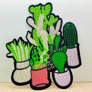 May include: Embroidered patch featuring a collection of potted plants. The patch includes a cactus, a succulent, and a variety of leafy plants. The plants are all in white pots with green and white details. The patch is perfect for adding a touch of nature to any project.