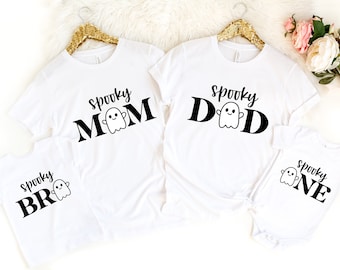 Puede incluir: Cuatro camisetas blancas con texto negro y un gráfico de fantasma. Las camisetas dicen "Spooky Mom", "Spooky Dad", "Spooky Bro" y "Spooky One".