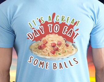 May include: Light blue t-shirt with a graphic of a plate of spaghetti and meatballs with the text "It's a great day to eat some balls".