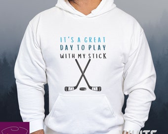 Può includere: Felpa con cappuccio bianca con una grafica blu e bianca che dice "È un grande giorno per giocare con la mia mazza" e un paio di bastoni da hockey incrociati con un disco.