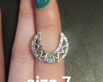 May include: Silver crescent moon ring with a turquoise stone in the center. The ring is size 7.