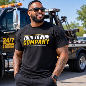 May include: A black short-sleeved t-shirt featuring the white and yellow text 'YOUR TOWING COMPANY' and '24 Hour Roadside Assistance' printed on the chest. The shirt has a crew neckline and a standard fit, made of a solid black fabric.