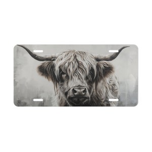 May include: A close-up portrait of a white Highland cow with long, shaggy hair. The cow is looking directly at the camera with a serious expression. The background is a soft, blurred gray.