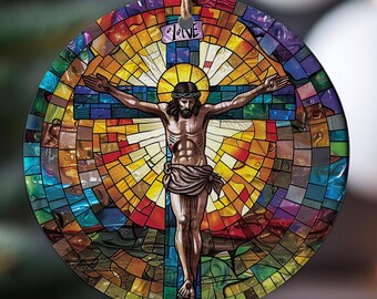 May include: A stained glass ornament featuring a colorful depiction of Jesus Christ on the cross. The background is a mosaic of red, yellow, blue, and green glass.