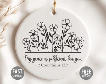 May include: A white ceramic ornament featuring a floral design and the text "My grace is sufficient for you 2 Corinthians 12:9". The ornament has a gold string for hanging. Includes "Fast Shipping" and "Free Gift Box" labels.
