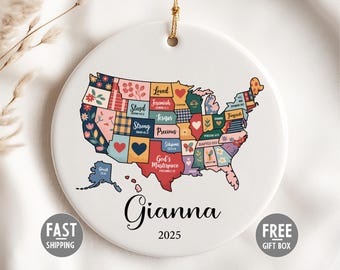 May include: A white ceramic ornament with a colourful map of the United States, decorated with floral and heart motifs. The name "Gianna" and the year "2025" are written below the map. A gold string is attached for hanging.