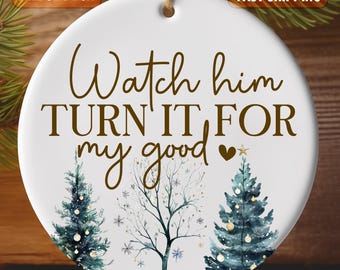 以下が含まれることがあります： 白いセラミック製のクリスマスオーナメントで、茶色の文字で「Watch him turn it for my good」とハートマークが書かれています。オーナメントには、水彩画で描かれた2本のスタイリッシュな木と雪の結晶がデザインされています。
