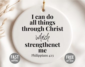 May include: A white, circular ceramic ornament featuring the text "I can do all things through Christ which strengthenet me" and "Philippians 4:13" in black. A gold string is attached for hanging.
