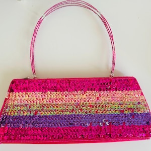 Pink sequin clutch with rainbow stripes, double handles, and shimmering accents. A unique evening purse for proms parties and special events