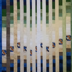 Op de afbeelding: Abstract textielkunstwerk met verticale strepen in tinten blauw, groen en beige. Het ontwerp bevat vierkanten stof met patronen met bloemen- en vlindermotieven, waardoor een dynamische compositie ontstaat.