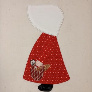 May include: A red dress with white polka dots and a white bonnet. The dress has a basket with a brown handle and a small white animal inside.