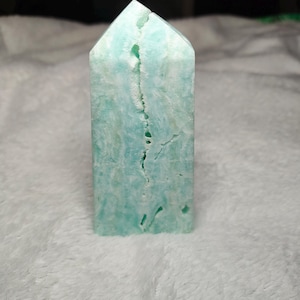 May include: A light blue, translucent, crystal point with a crack running down the center. The crystal is smooth and polished.
