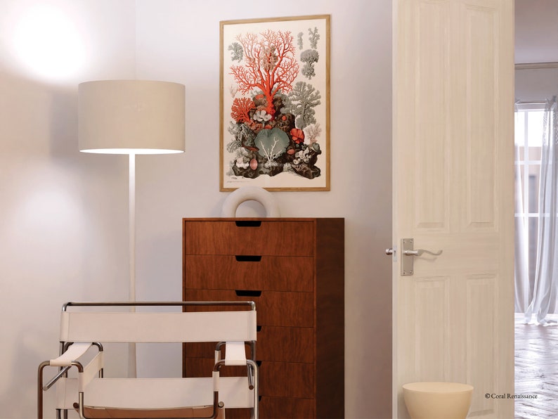 Peut inclure: Une lampe blanche avec un abat-jour en tissu blanc se trouve &agrave; c&ocirc;t&eacute; d'un fauteuil blanc avec une structure en bois. Une commode &agrave; quatre tiroirs se trouve derri&egrave;re le fauteuil. Une estampe encadr&eacute;e de corail et d'autres formes de vie marine est accroch&eacute;e au mur. La porte est ouverte sur une pi&egrave;ce avec des rideaux blancs.