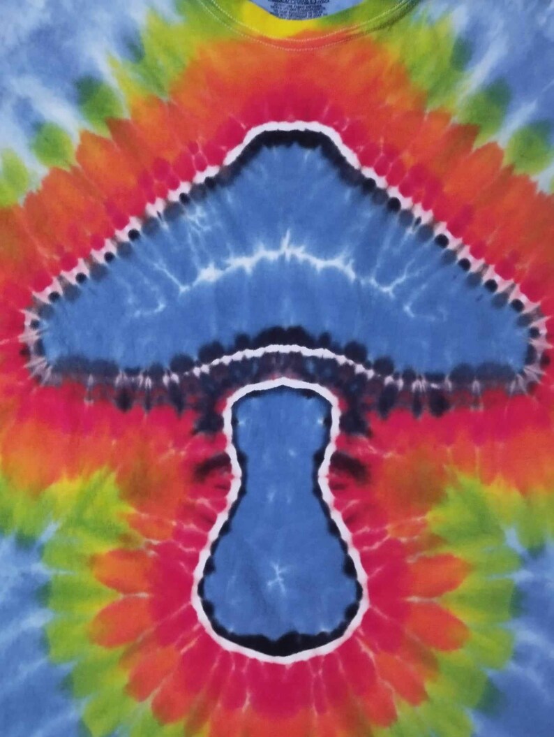 May include: Tie-dye shirt with a colorful psychedelic mushroom design. The mushroom is blue with a white outline and a black stem.