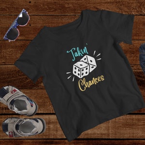 May include: Black t-shirt with white text that says "Takin' Chances" and a graphic of two dice.