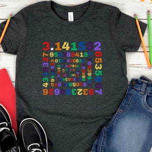 May include: A dark grey t-shirt featuring a colourful design of the digits of pi arranged in a square. The numbers are in a rainbow of colours, including red, orange, yellow, green, blue, indigo, and violet.