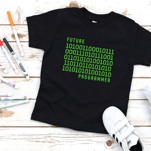 May include: Black t-shirt with green text that reads "FUTURE 101001100010111 000111010111001 011010101001010 110111010101010 101010101001010 PROGRAMMER"