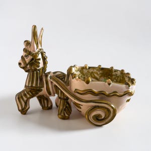 May include: A ceramic donkey-pulled cart planter. The donkey is light pink with olive green accents. The cart is light pink with a wavy rim and olive green interior. The cart has a decorative swirl on the side.