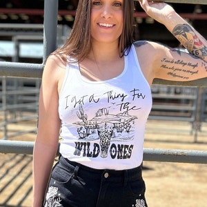 May include: White tank top with a black and white graphic of a longhorn skull with the text "I got a thing for the wild ones".