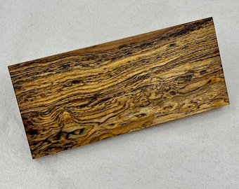 Puede incluir: Primer plano de una tabla de madera rectangular con un patrón de veta de madera marrón oscuro y negro.