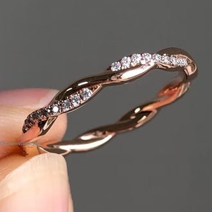 Op de afbeelding: Een delicate roségouden band met een gedraaid ontwerp en kleine diamanten die langs de bovenkant zijn gezet.