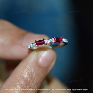 May include: A silver ring with a row of small diamonds and two red rectangular gemstones.